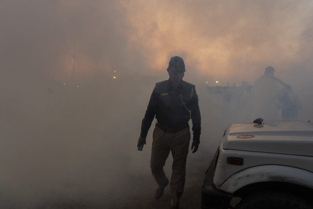 A policeman moving away from smoke in Delhi